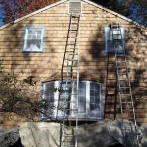 Taped off window and covered landscaping during exterior house painting